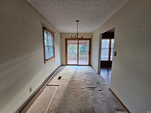 unfurnished dining area featuring a textured ceiling, a baseboard heating unit, a chandelier, and carpet floors