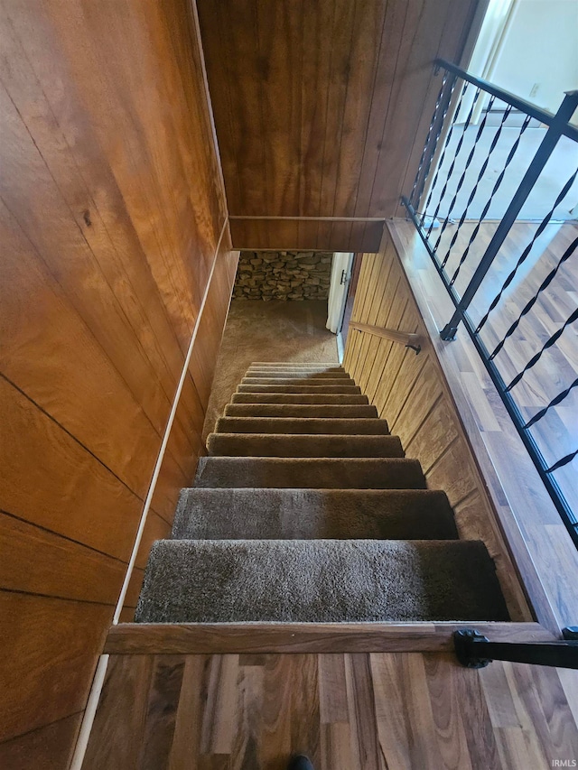 staircase with wooden walls, wood-type flooring, and wooden ceiling