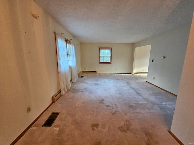 carpeted empty room with a baseboard radiator and a textured ceiling