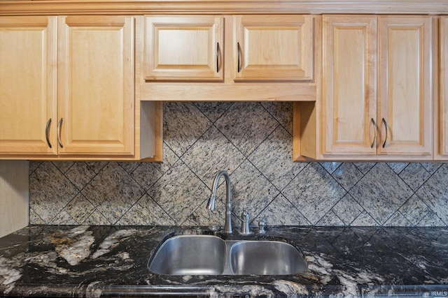 kitchen with dark stone countertops, decorative backsplash, sink, and light brown cabinets