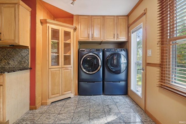 clothes washing area featuring a wealth of natural light, separate washer and dryer, and cabinets