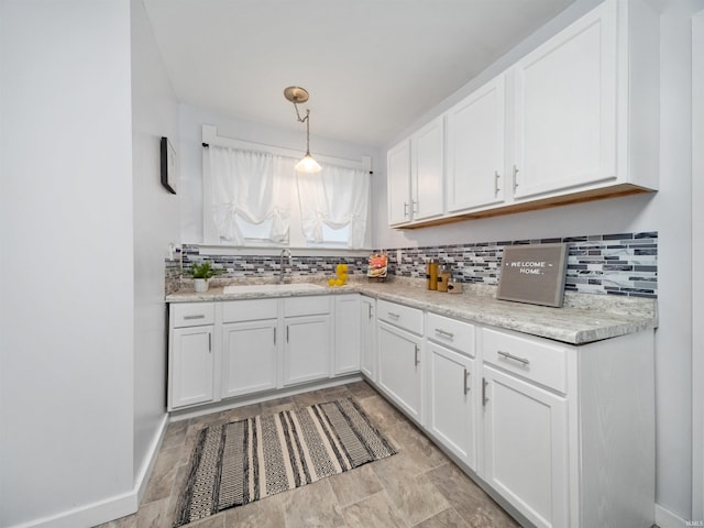 kitchen featuring white cabinetry, sink, backsplash, and pendant lighting