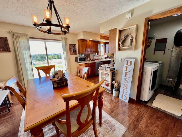 dining area with dark wood-type flooring, washer and dryer, a textured ceiling, and an inviting chandelier