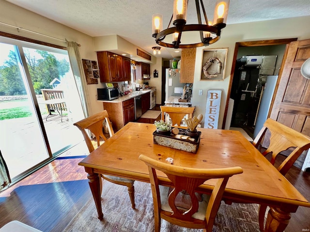 dining space with a textured ceiling, a chandelier, and light wood-type flooring