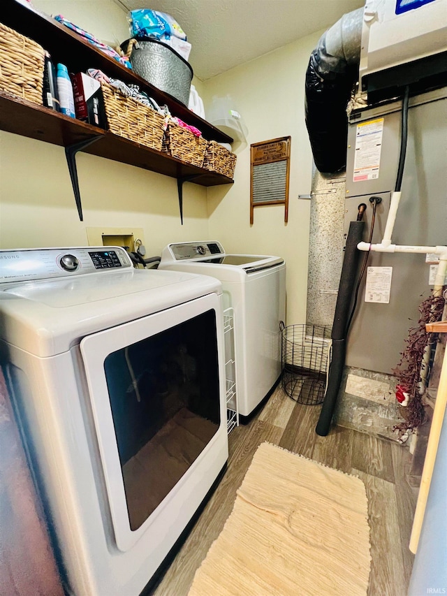 laundry room featuring washing machine and dryer, heating unit, and hardwood / wood-style flooring