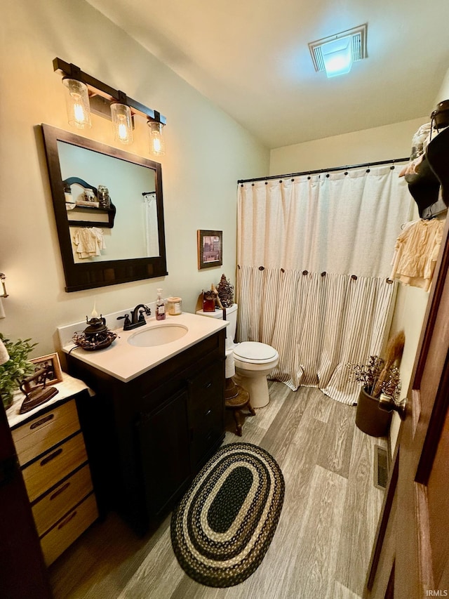 bathroom featuring vanity, hardwood / wood-style floors, toilet, and walk in shower