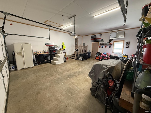 garage with a garage door opener, white fridge with ice dispenser, and a workshop area