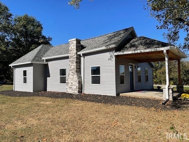 rear view of property featuring a yard and a patio area