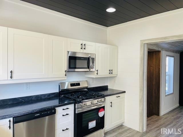 kitchen featuring crown molding, stainless steel appliances, light hardwood / wood-style flooring, and white cabinets