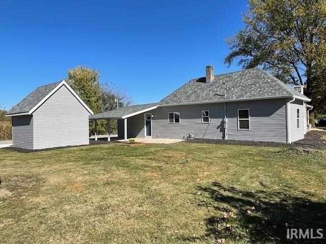 back of property featuring a yard and a storage unit