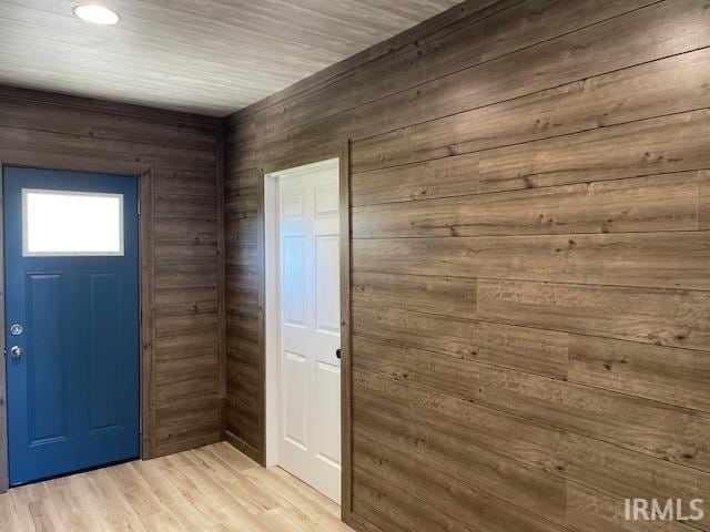 entryway with wood walls and light hardwood / wood-style flooring