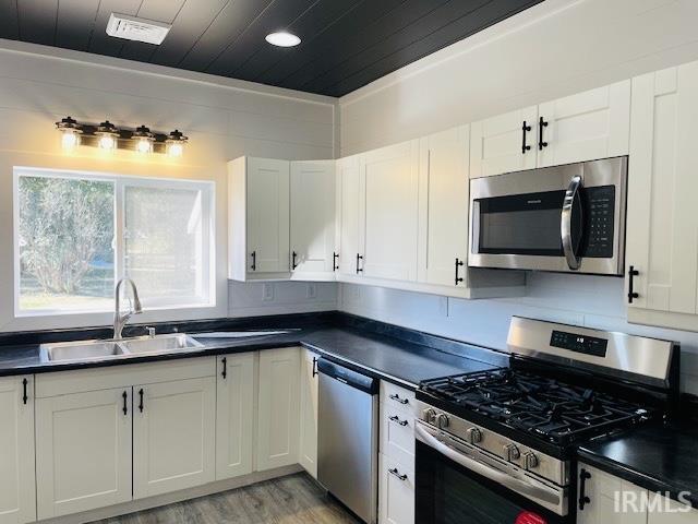 kitchen with sink, white cabinetry, stainless steel appliances, and light wood-type flooring