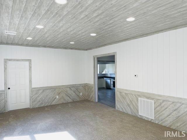 unfurnished room with wood walls and carpet floors