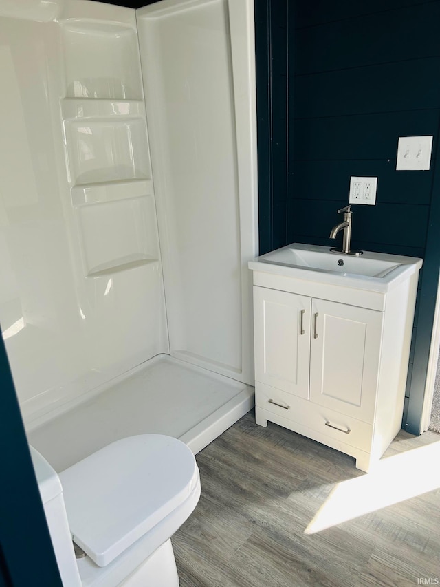 bathroom featuring toilet, walk in shower, vanity, and wood-type flooring