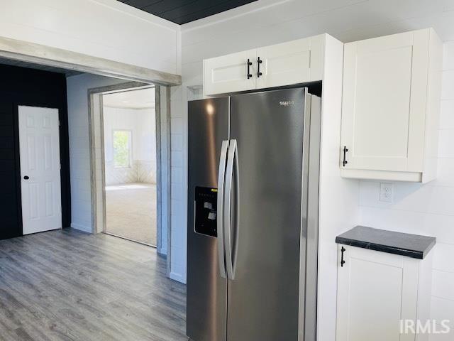 kitchen with light hardwood / wood-style floors, white cabinets, and stainless steel fridge with ice dispenser