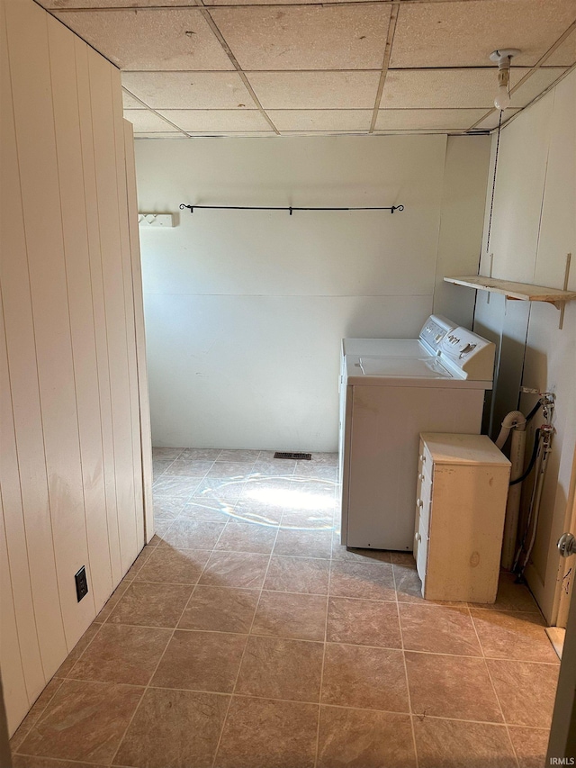 laundry room with independent washer and dryer, wood walls, and light tile patterned flooring