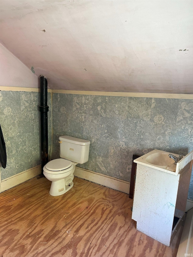 bathroom with sink, toilet, hardwood / wood-style flooring, and vaulted ceiling