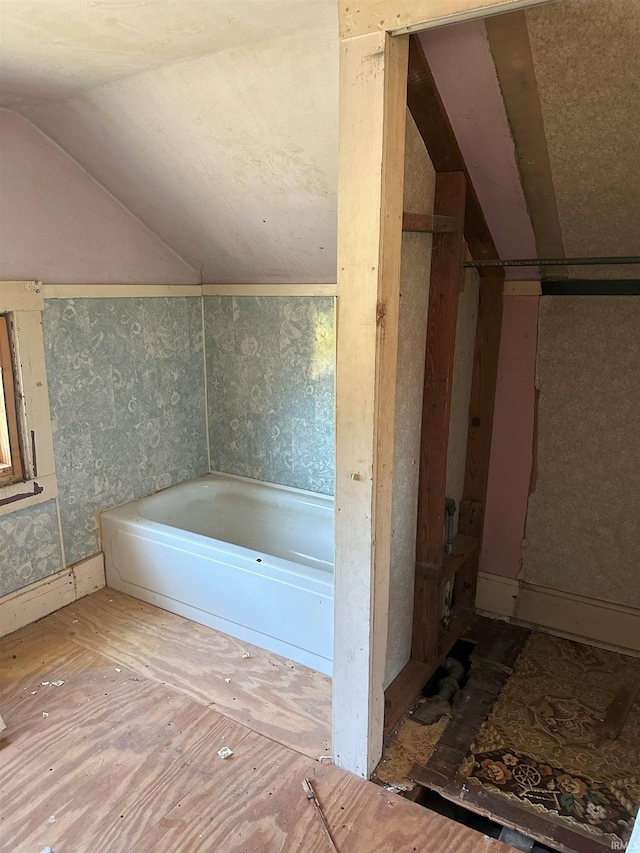 bathroom featuring a bathtub and lofted ceiling