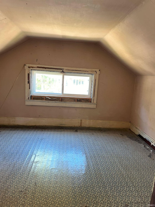 additional living space featuring vaulted ceiling, carpet flooring, and a healthy amount of sunlight