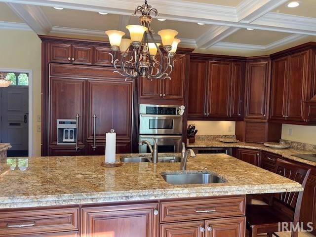 kitchen with light stone counters, a chandelier, sink, double oven, and decorative light fixtures