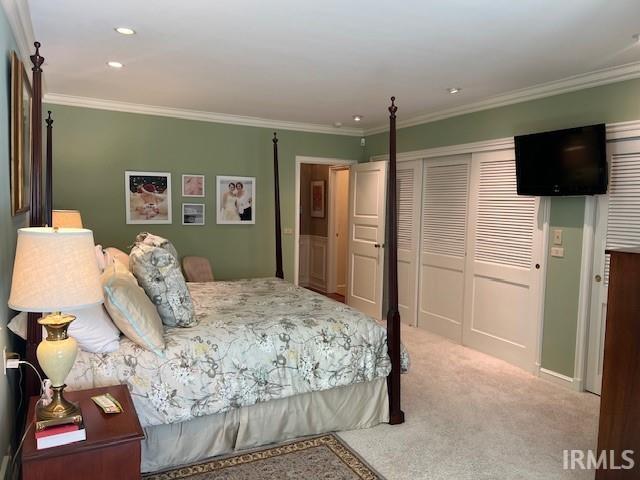 bedroom featuring a closet, light carpet, and crown molding