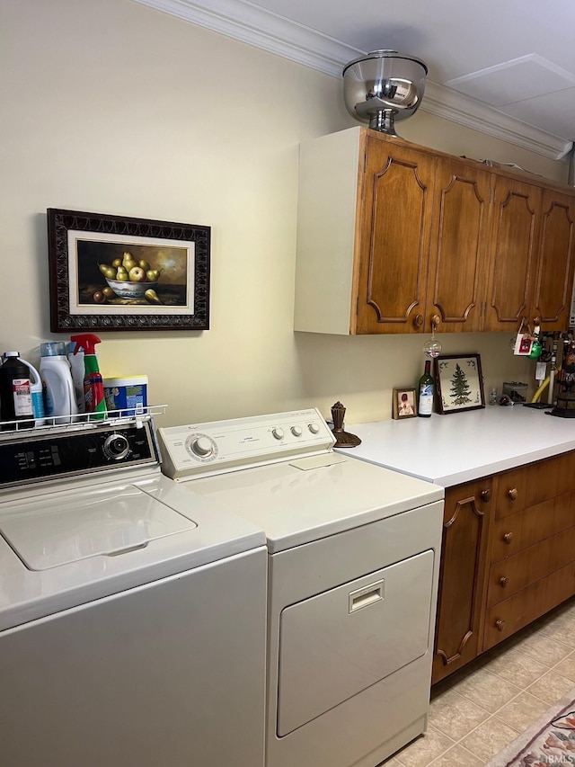 washroom with crown molding, washing machine and dryer, light tile patterned floors, and cabinets