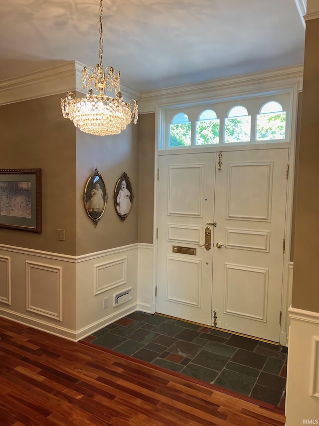 entryway with an inviting chandelier, ornamental molding, plenty of natural light, and dark hardwood / wood-style flooring