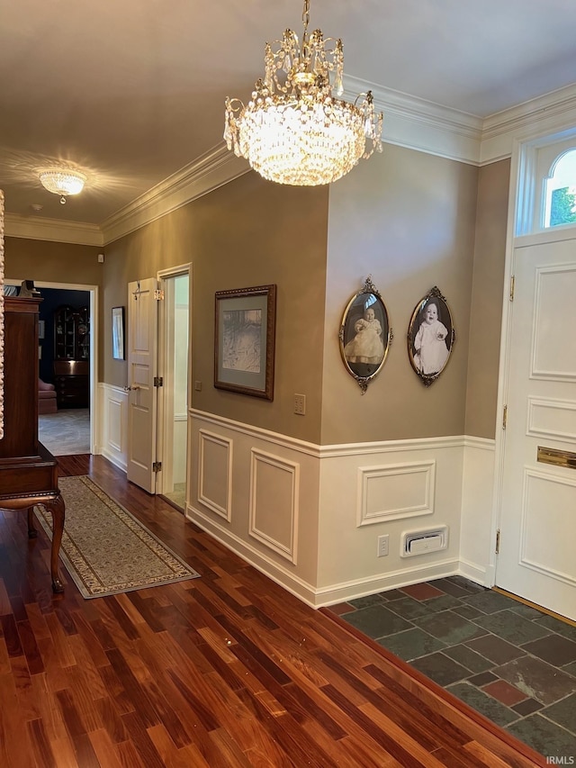 foyer with dark wood-type flooring, a notable chandelier, and crown molding