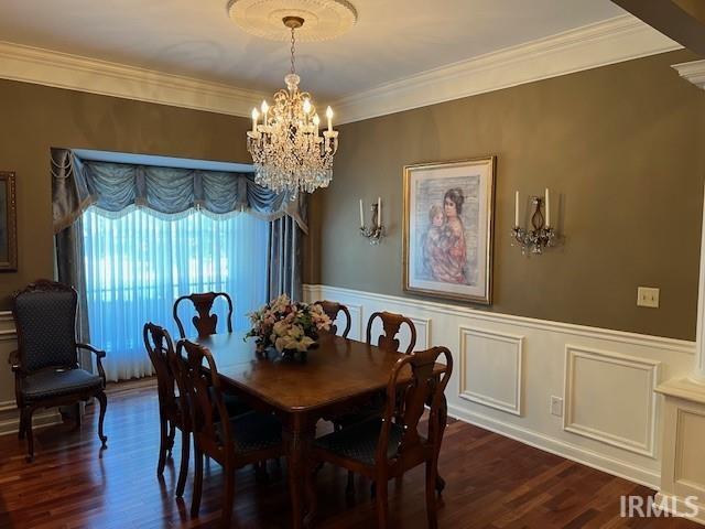 dining room with decorative columns, crown molding, a notable chandelier, and dark hardwood / wood-style flooring