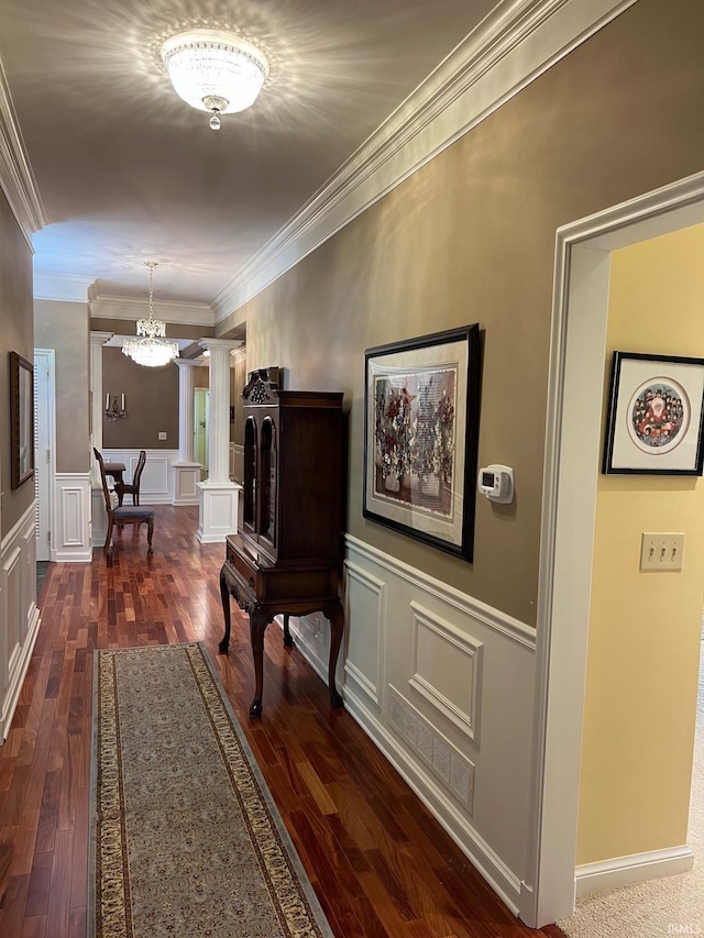 hallway with ornamental molding, ornate columns, dark hardwood / wood-style floors, and an inviting chandelier