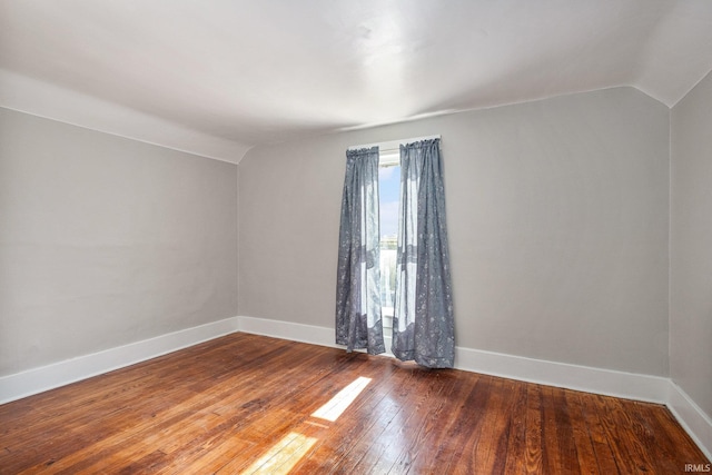 unfurnished room featuring lofted ceiling and hardwood / wood-style floors