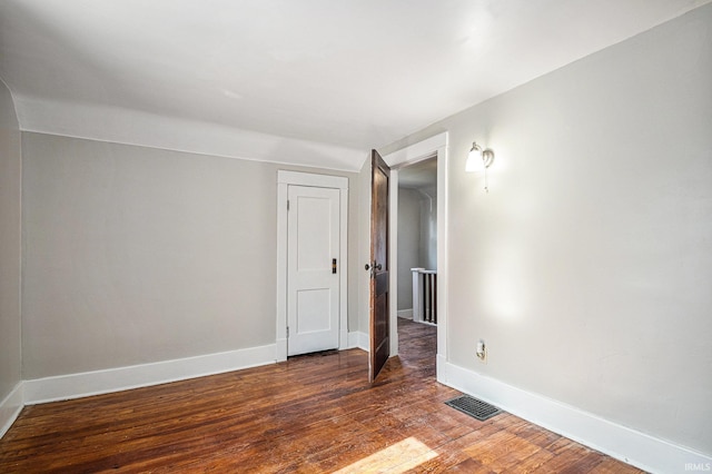 unfurnished room with dark wood-type flooring