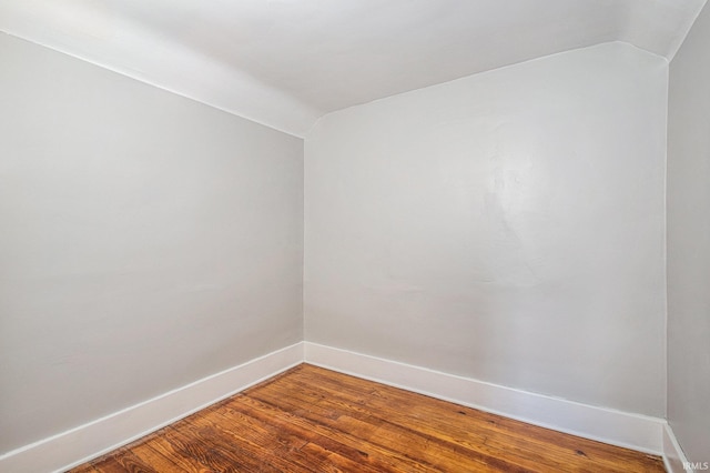 unfurnished room with lofted ceiling and hardwood / wood-style floors