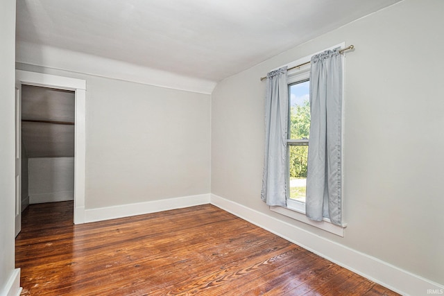 spare room with dark hardwood / wood-style flooring, plenty of natural light, and vaulted ceiling