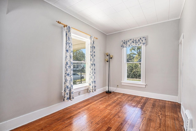 spare room with ornamental molding, a wealth of natural light, and hardwood / wood-style floors