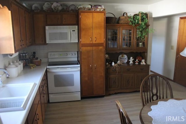 kitchen featuring white appliances, light hardwood / wood-style flooring, tasteful backsplash, and sink