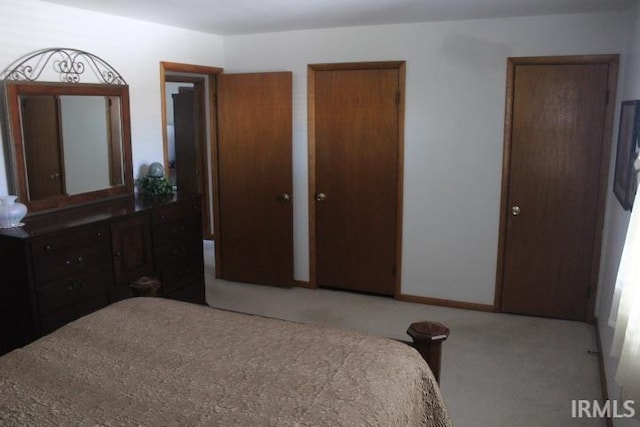 bedroom featuring multiple closets and light colored carpet