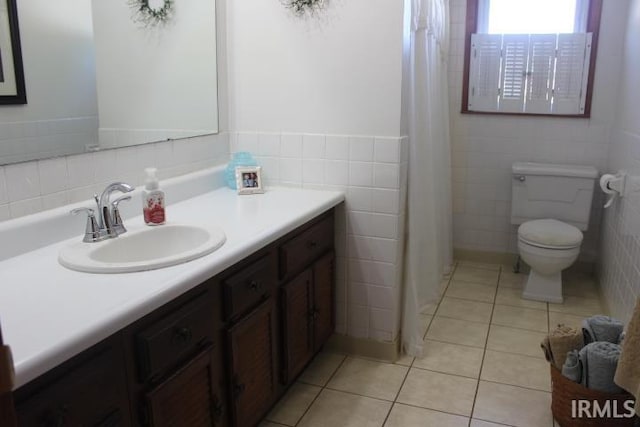 bathroom with toilet, vanity, tile patterned floors, and tile walls