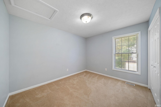 carpeted empty room with a textured ceiling