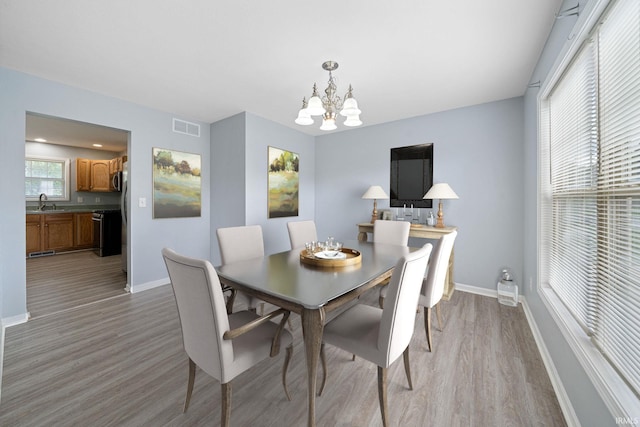 dining area with light hardwood / wood-style floors, a notable chandelier, and sink