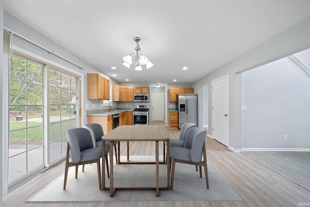 kitchen featuring appliances with stainless steel finishes, an inviting chandelier, light hardwood / wood-style flooring, pendant lighting, and sink