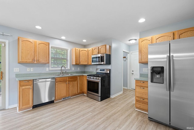 kitchen featuring stainless steel appliances, light brown cabinetry, sink, and light wood-type flooring