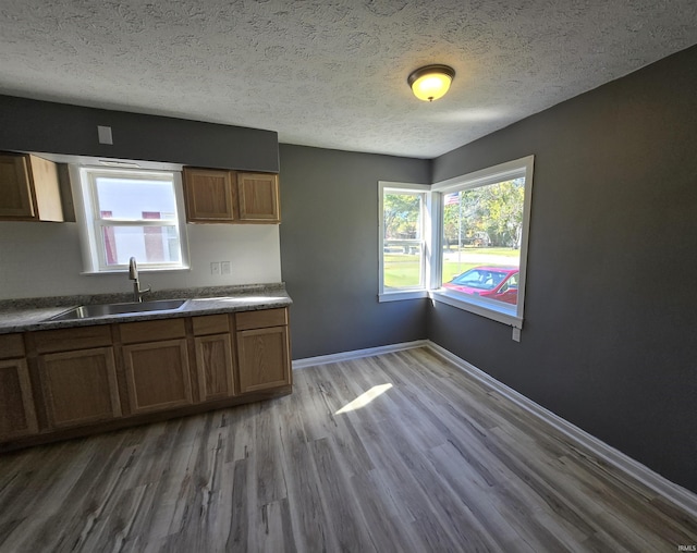 kitchen with a textured ceiling, wood-type flooring, and sink