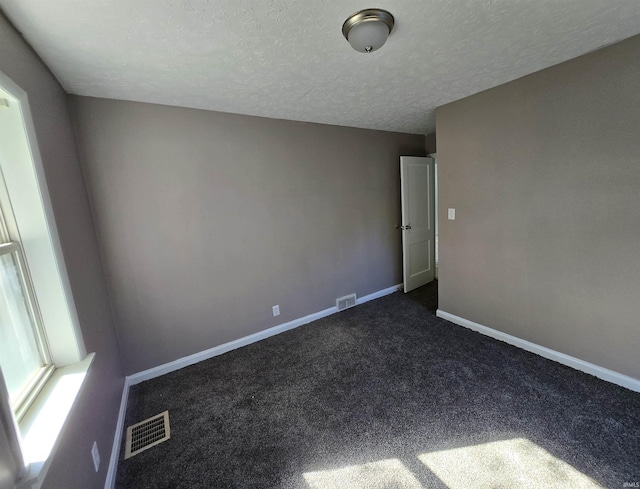 unfurnished room with dark carpet and a textured ceiling