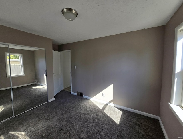 unfurnished bedroom featuring a closet, a textured ceiling, and dark colored carpet