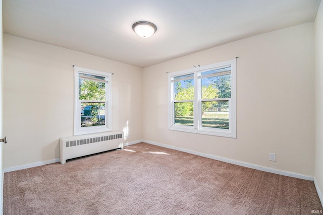 unfurnished room featuring radiator heating unit and light colored carpet