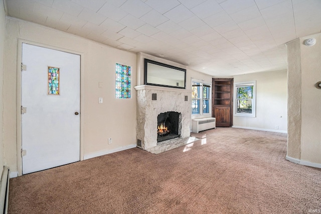 unfurnished living room featuring radiator and carpet