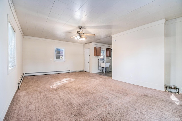 unfurnished living room featuring sink, a baseboard heating unit, ornamental molding, ceiling fan, and carpet