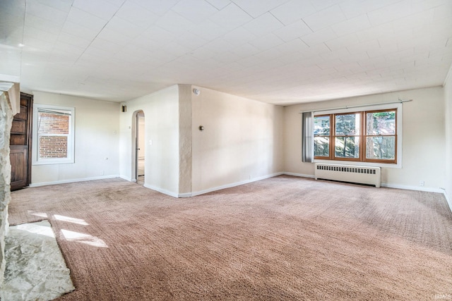 unfurnished living room featuring radiator and carpet flooring