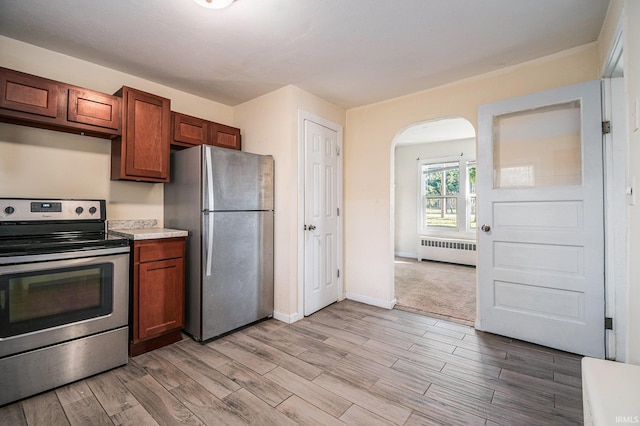 kitchen featuring radiator, stainless steel appliances, and light hardwood / wood-style flooring